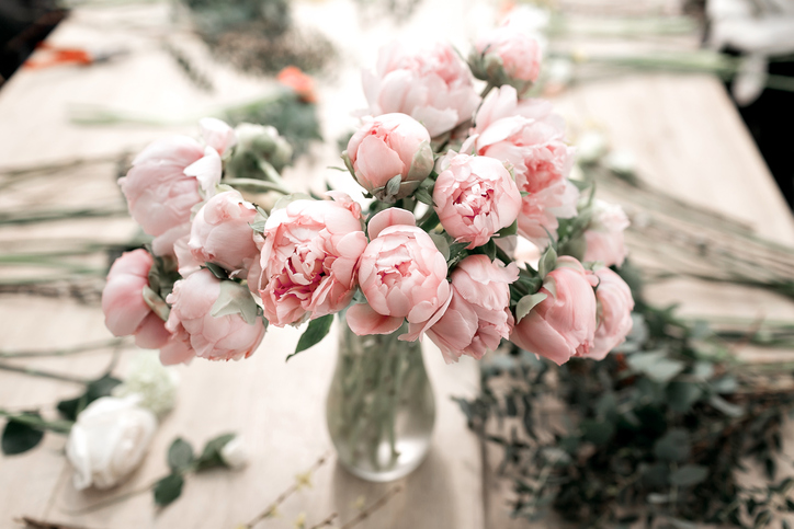 Pink peonies in vase on wooden floor and bokeh background - retro styled photo. soft focus.