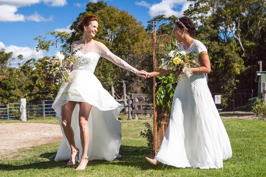 Two brides meet at the start of the aisle on their wedding day