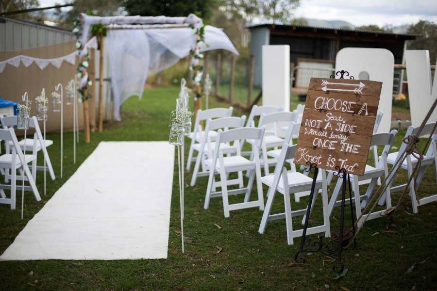 A wedding ceremony set up with a sign that reads" choose a seat not a side"