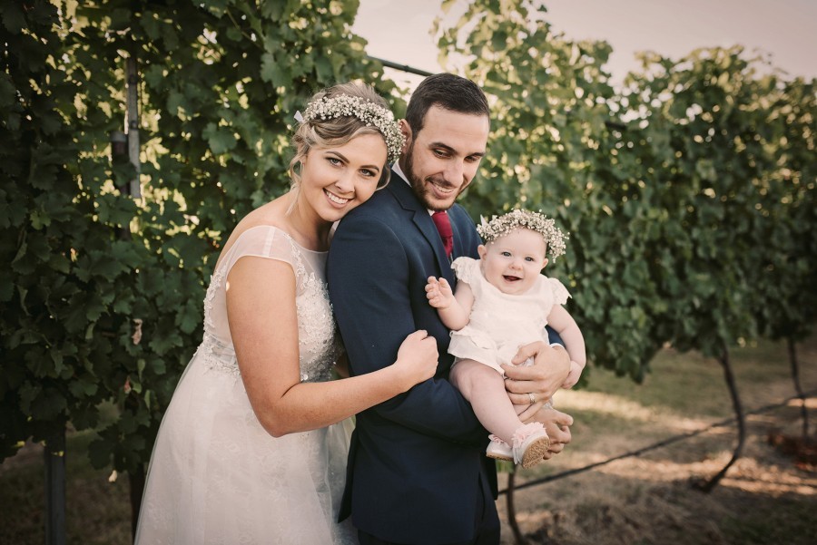 bride and groom on their wedding day with their baby daughter