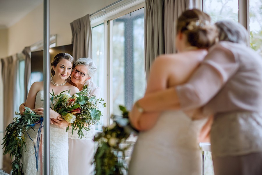 Bride looking in mirror being hugged by her mother