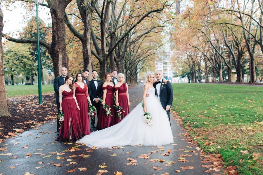 Bridal party and bride and groom pose in melbourne's carlton gardens in winter
