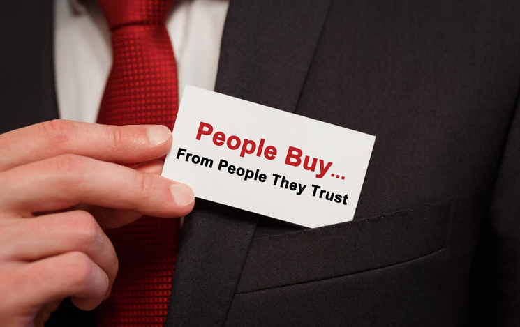 Businessman putting a card with text People Buy From People They Trust in the pocket