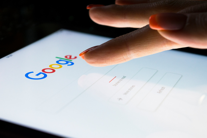 A woman's hand is touching screen on tablet computer iPad Pro at night for searching on Google search engine. Google is the most popular Internet search engine in the world.