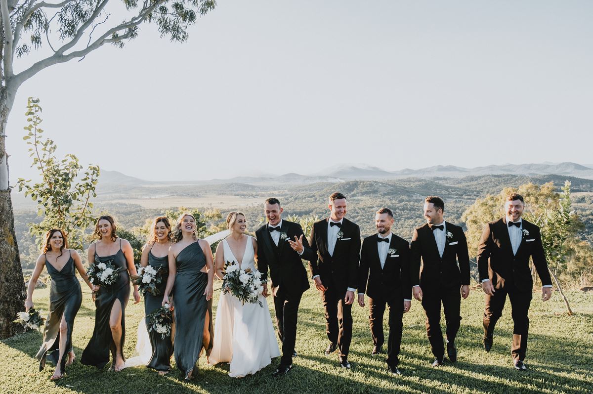 A wedding party walks up a hill