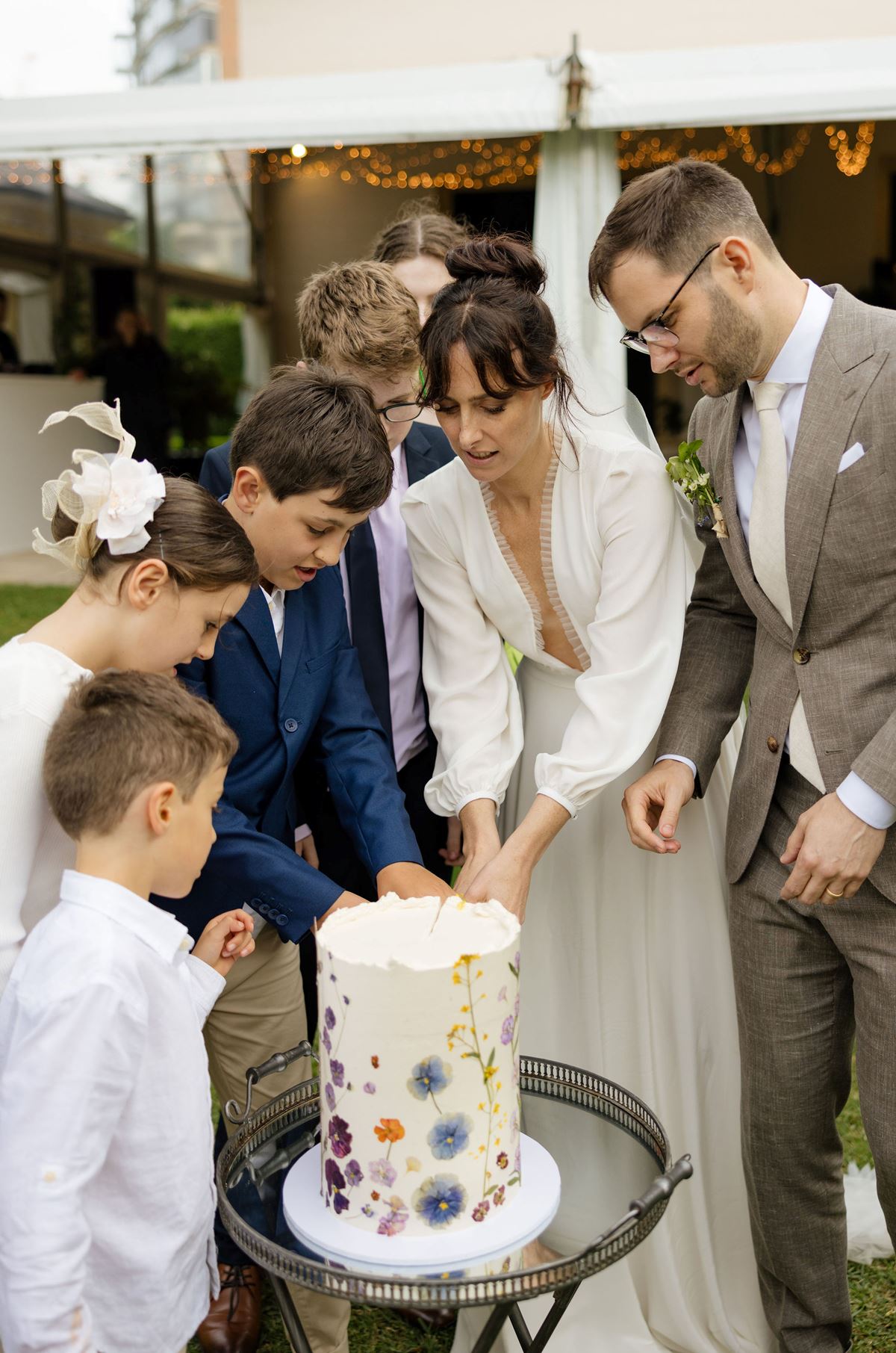 bride cuts her wedding cake with family