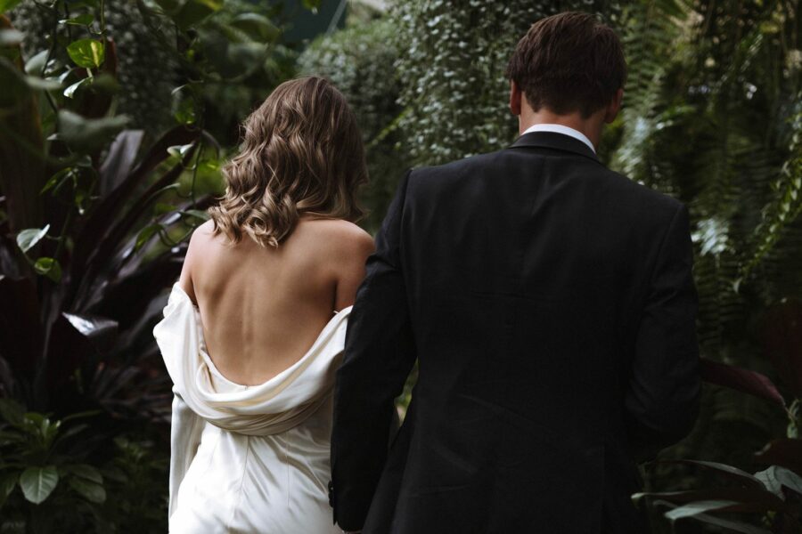 Bride and groom with leaves and trees from behind