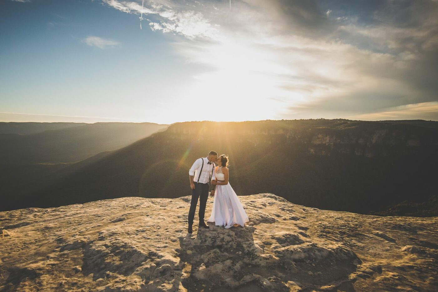 A couple share a kiss on a cliff face