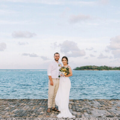 Couple celebrating a romantic destination wedding by the ocean at a tropical resort