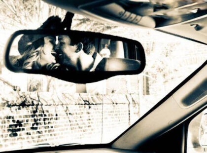 couple kisses in a rear view mirror