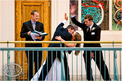 a groom kisses the bride and high-fives his best man
