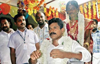 Prethush and Rekha wheel their way down the aisle during their hospital wedding